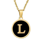 Gouden hangerketting met de letter ’L’ op een zwarte ronde achtergrond.