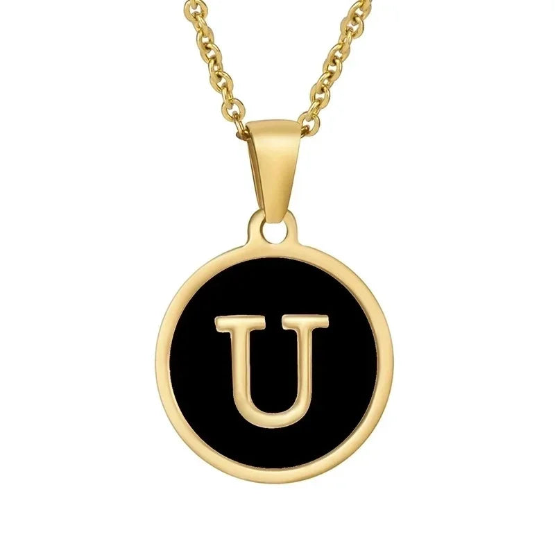 Goudkleurige hangerketting met de letter ’U’ op een zwarte ronde achtergrond.