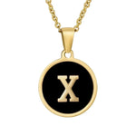 Hanger met vergulde ketting met de letter ’X’ op een zwarte ronde achtergrond.