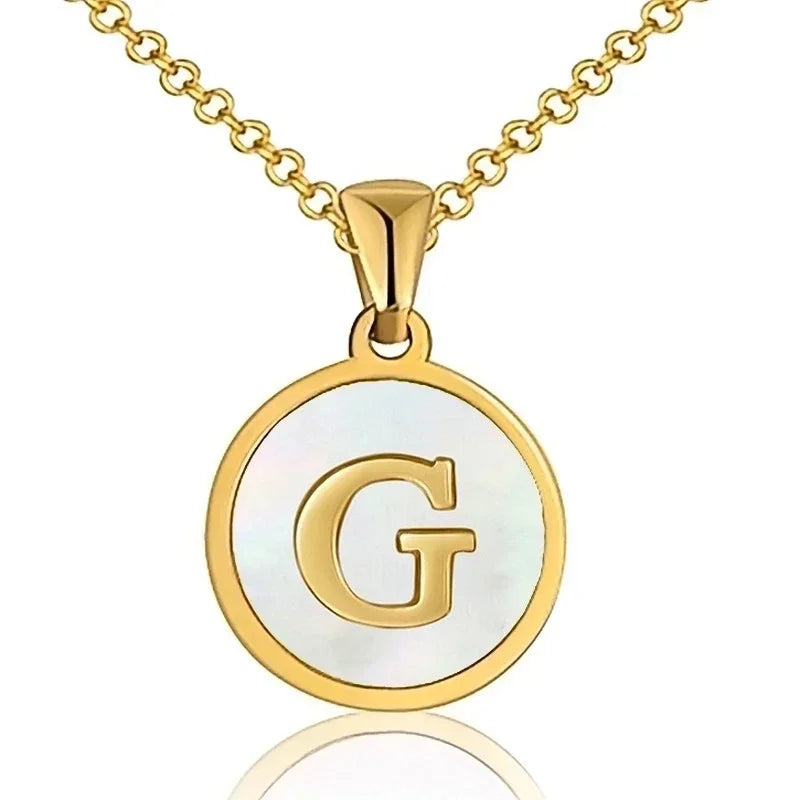 Hanger met vergulde ketting met de letter ’G’ op een witte ronde achtergrond.