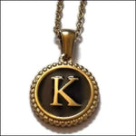 Een gouden ketting met een zwart-witte letter k