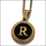 Een gouden ketting met een zwarte letter r erop