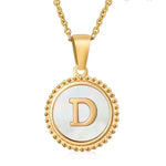 Hanger met vergulde ketting met de letter ’D’ op een witte ronde achtergrond met kralenrand.