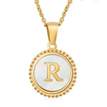 Hanger met vergulde ketting met de letter ’R’ op een parelmoeren achtergrond met kralenrand.