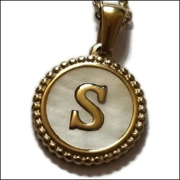 Een gouden hanger met een letter s in het midden