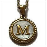 Een gouden hanger met de letter m erin