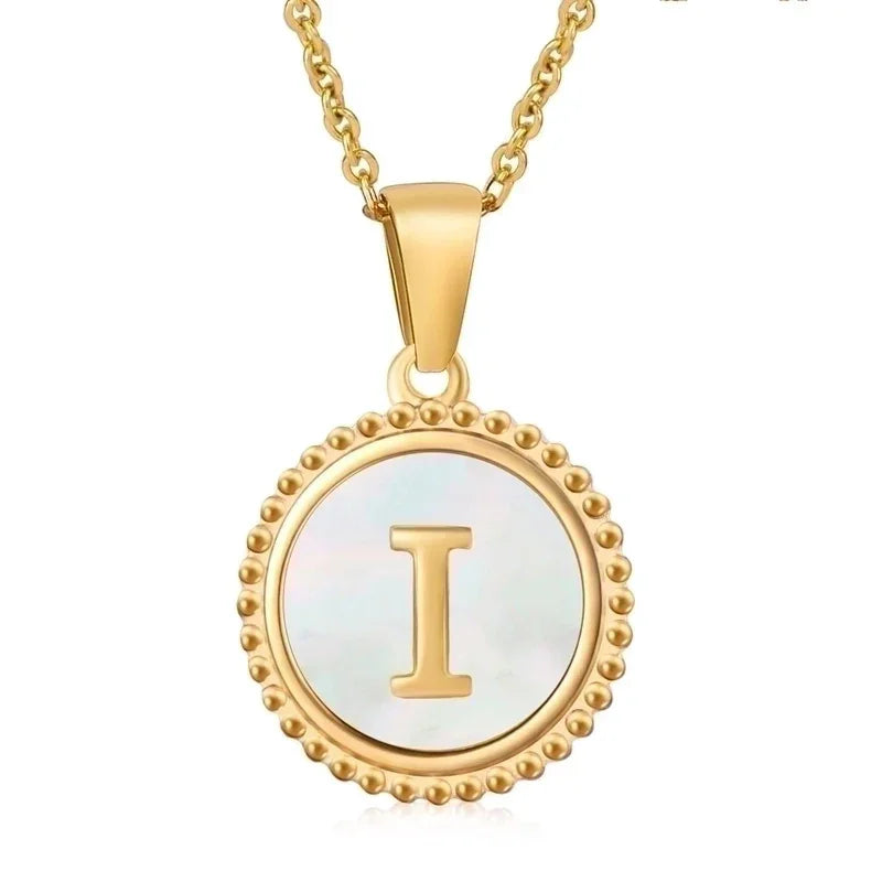 Hanger met vergulde ketting met de letter ’I’ op een parelmoeren schijf met kralenrand.