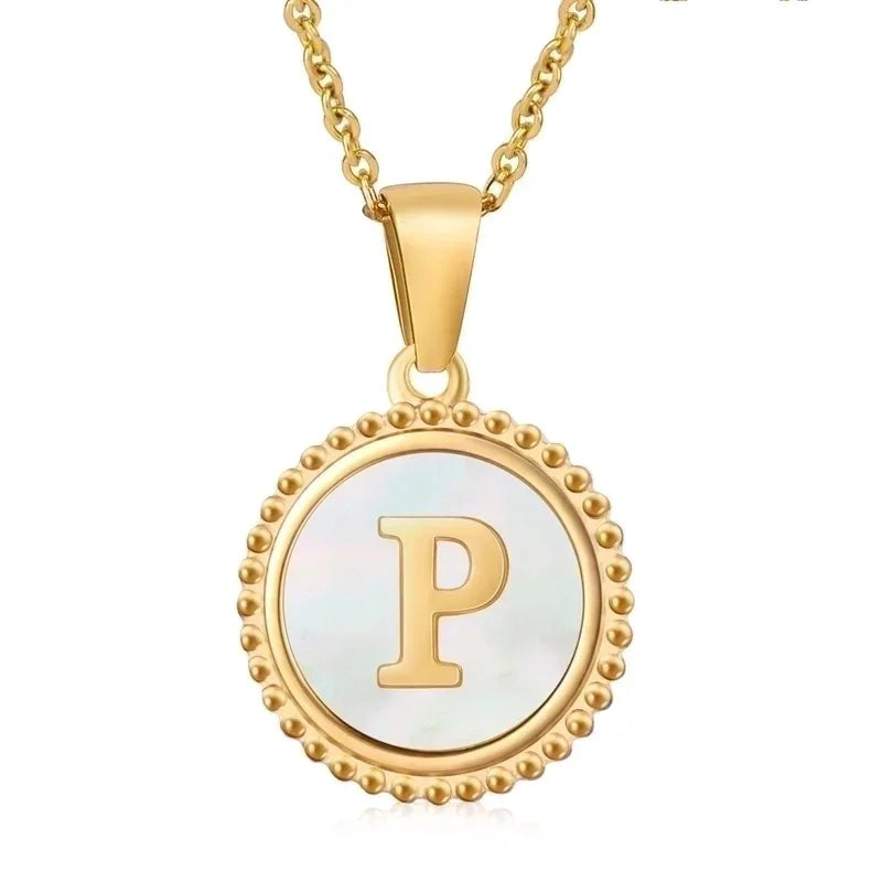 Hanger met vergulde ketting met de letter ’P’ op een parelmoeren achtergrond met kralenrand.