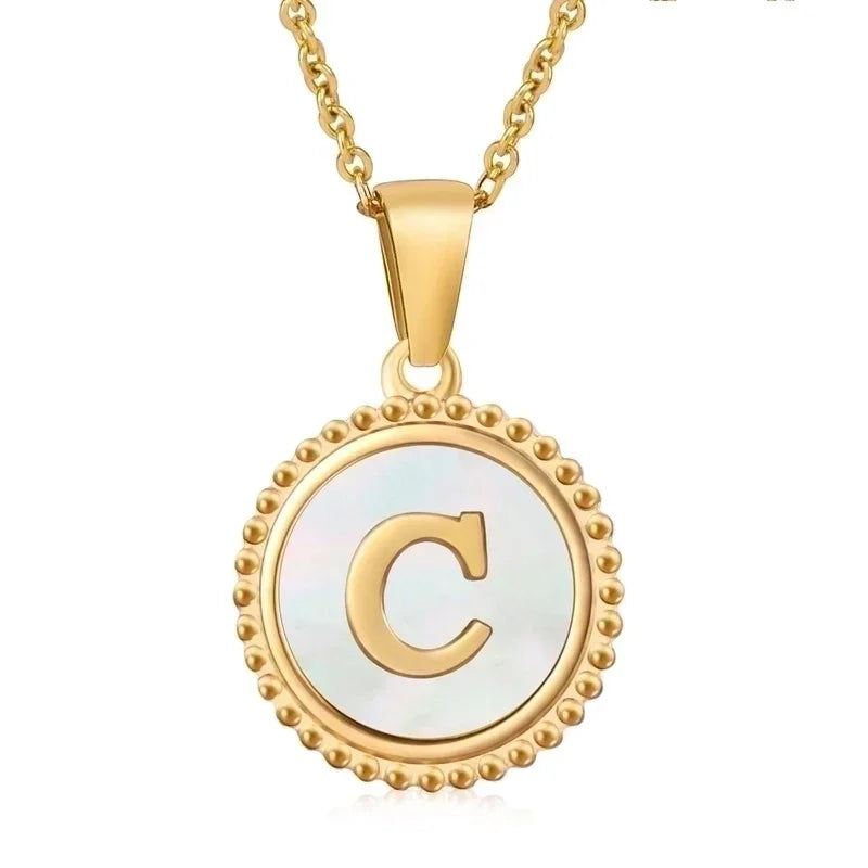 Hanger met vergulde ketting met de letter ’C’ op een witte ronde achtergrond met kralenrand.