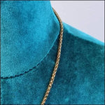 Een close-up van een gouden ketting op een blauwe jurk