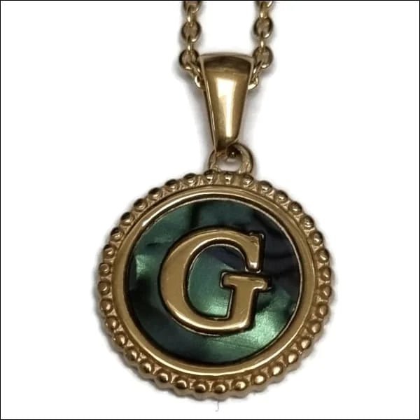 Een groen met gouden hanger met een letter g