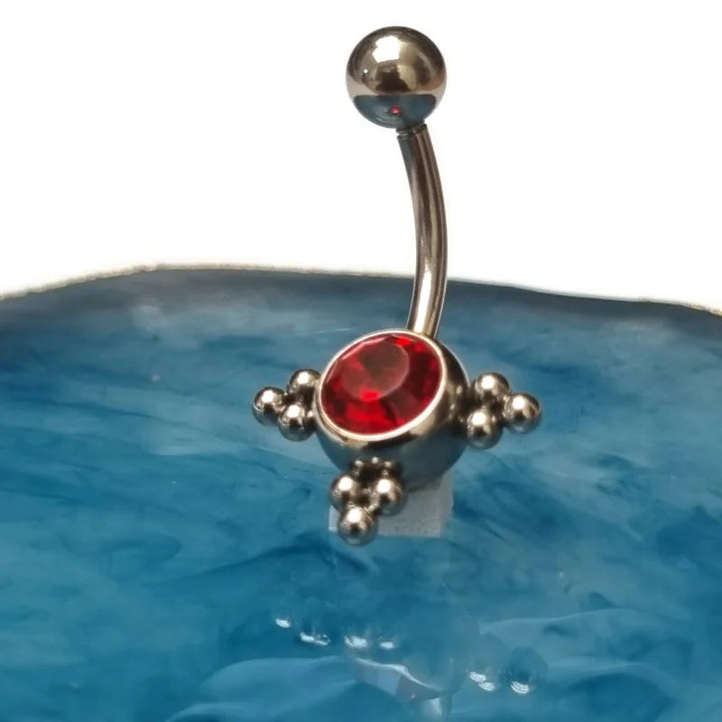 Rode Zirkonia Steen Op Blauwe Kom Voor Stalen Navelpiercing Met Zilverkleurige Dots.