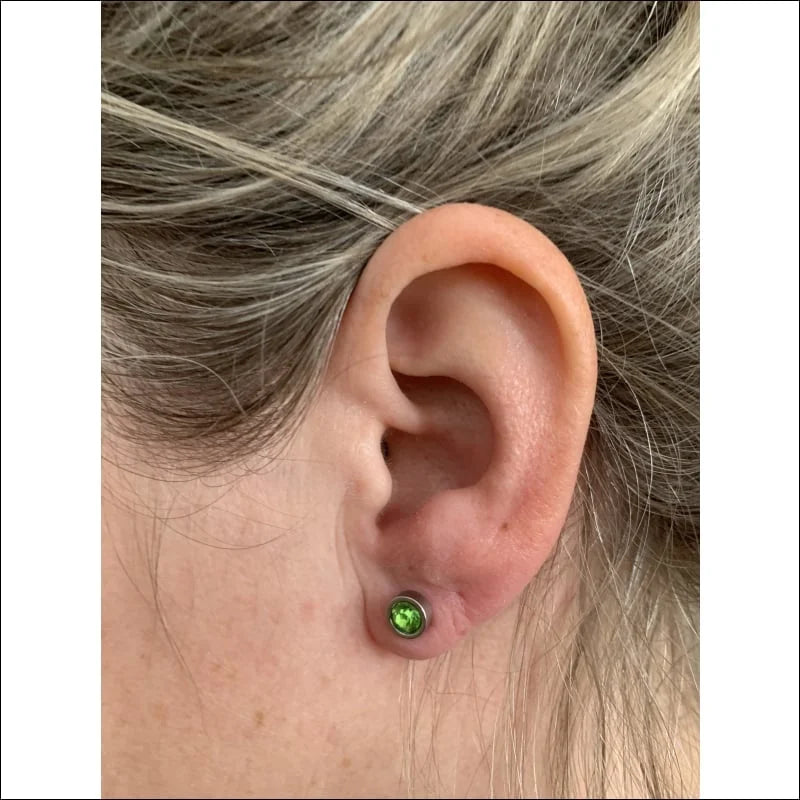 Lichtgroene Kristal Oorbel Van Aramat Jewels® Met Vrouw Met Groene Oorpiercing.