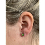 Lichtgroene Kristal Oorbel Van Aramat Jewels® Met Vrouw Met Groene Oorpiercing.