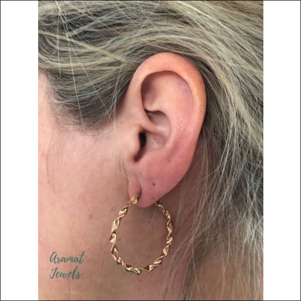 Vrouw Draagt ​​gouden Hoepeloorbel - Aramat Jewels®