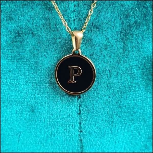 Een gouden ketting met een zwarte letter erop