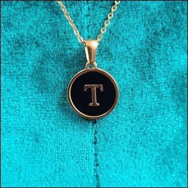 Een gouden ketting met een zwarte letter t erop