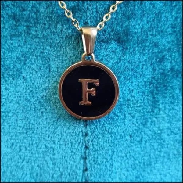 Een zwart met gouden initiaalketting met de letter f