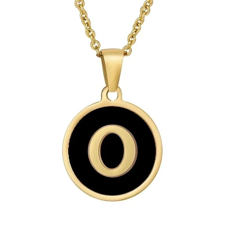 Gouden hangerketting met de letter ’O’ op een zwarte ronde achtergrond.