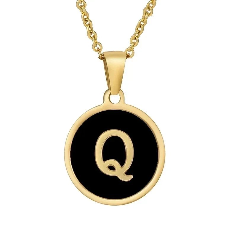 Gouden halsketting met de letter ’Q’ op een zwarte ronde achtergrond.