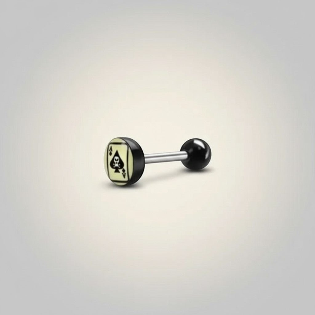 Aramat Jewels surgical steel tongue piercing with black acrylic balls and a spade card logo on a light yellow background.