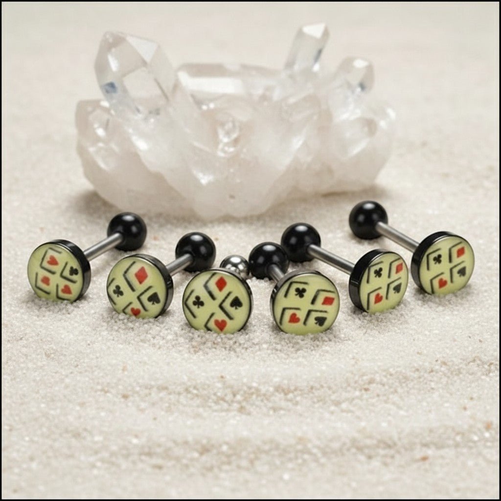 Aramat Jewels surgical steel tongue piercing with black acrylic balls and a cream-colored logo featuring playing card suits.