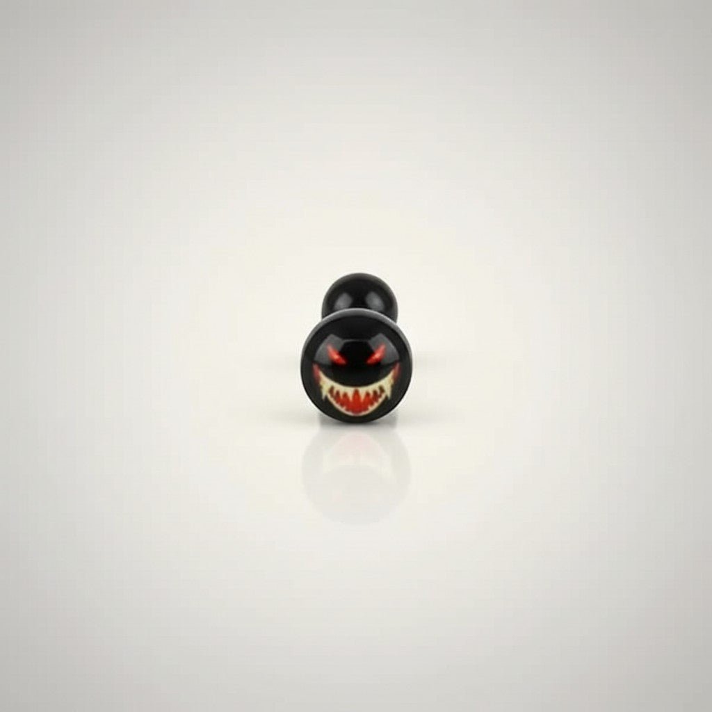 Aramat Jewels surgical steel tongue piercing with black acrylic logo featuring a spooky face with red eyes and sharp teeth.