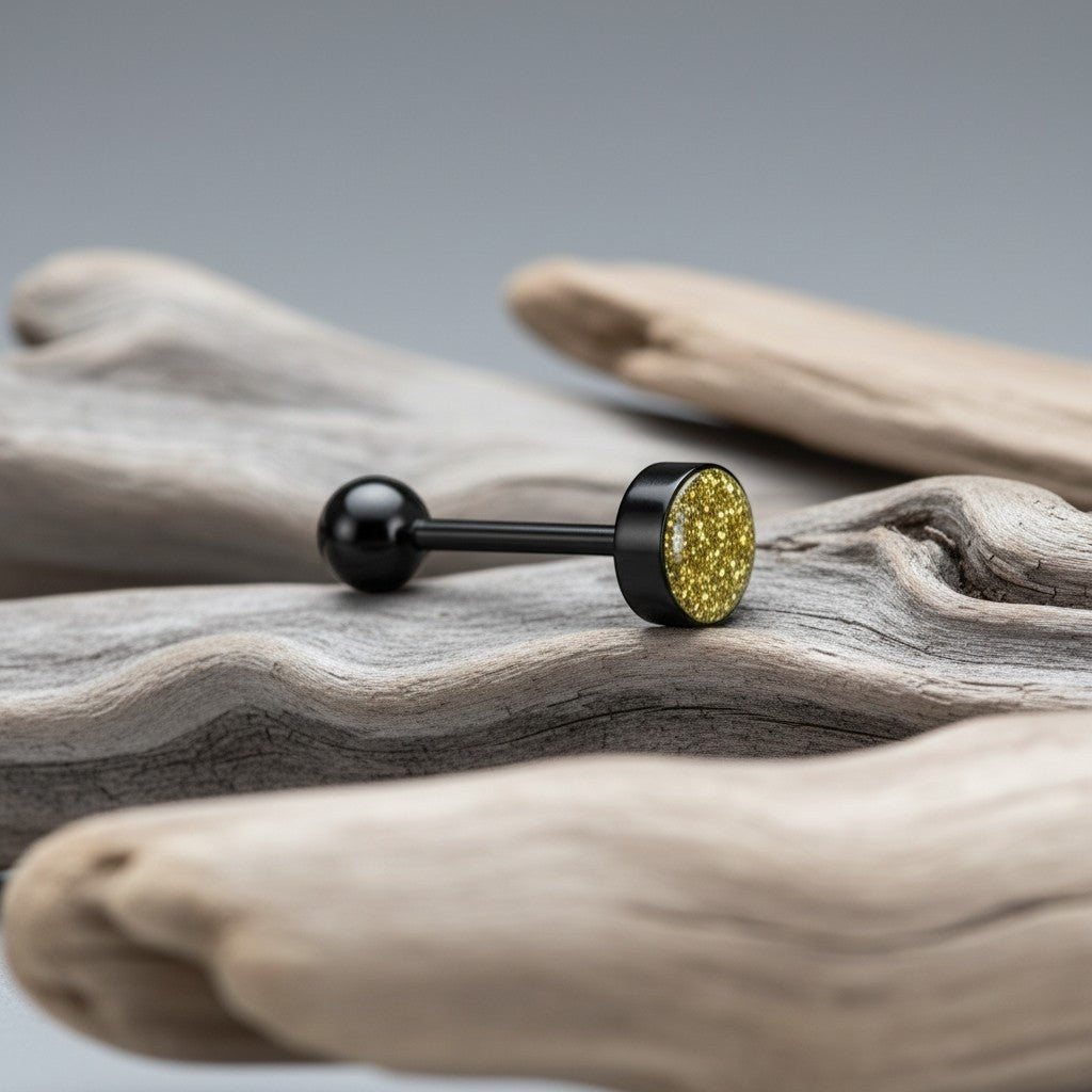 Aramat Jewels black bioplast tongue piercing with a glittery gold flat end and a black ball end.